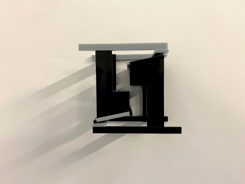 Two models, in grey and black plastic, of desk type structures.